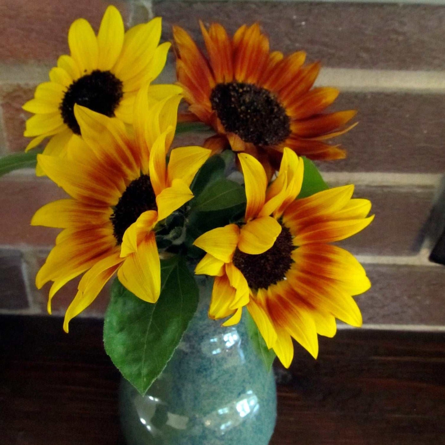 Sunflower Color Fashion bouquet with vibrant yellow, orange, and red blooms in a vase.