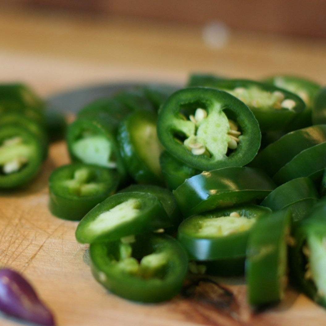 Non-treated heirloom Jalapeno pepper slices on wooden cutting board.