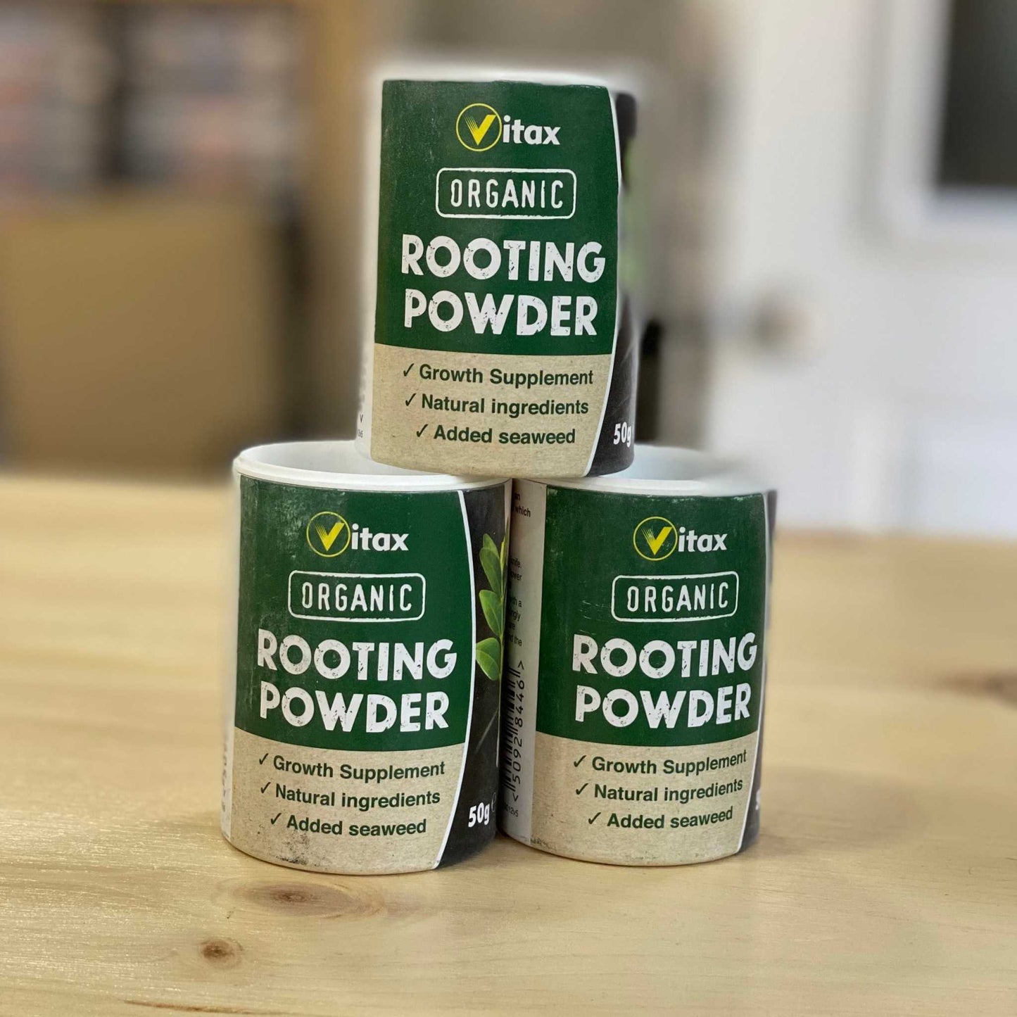 Organic Rooting Powder bottles with natural growth supplement label on a wooden table.