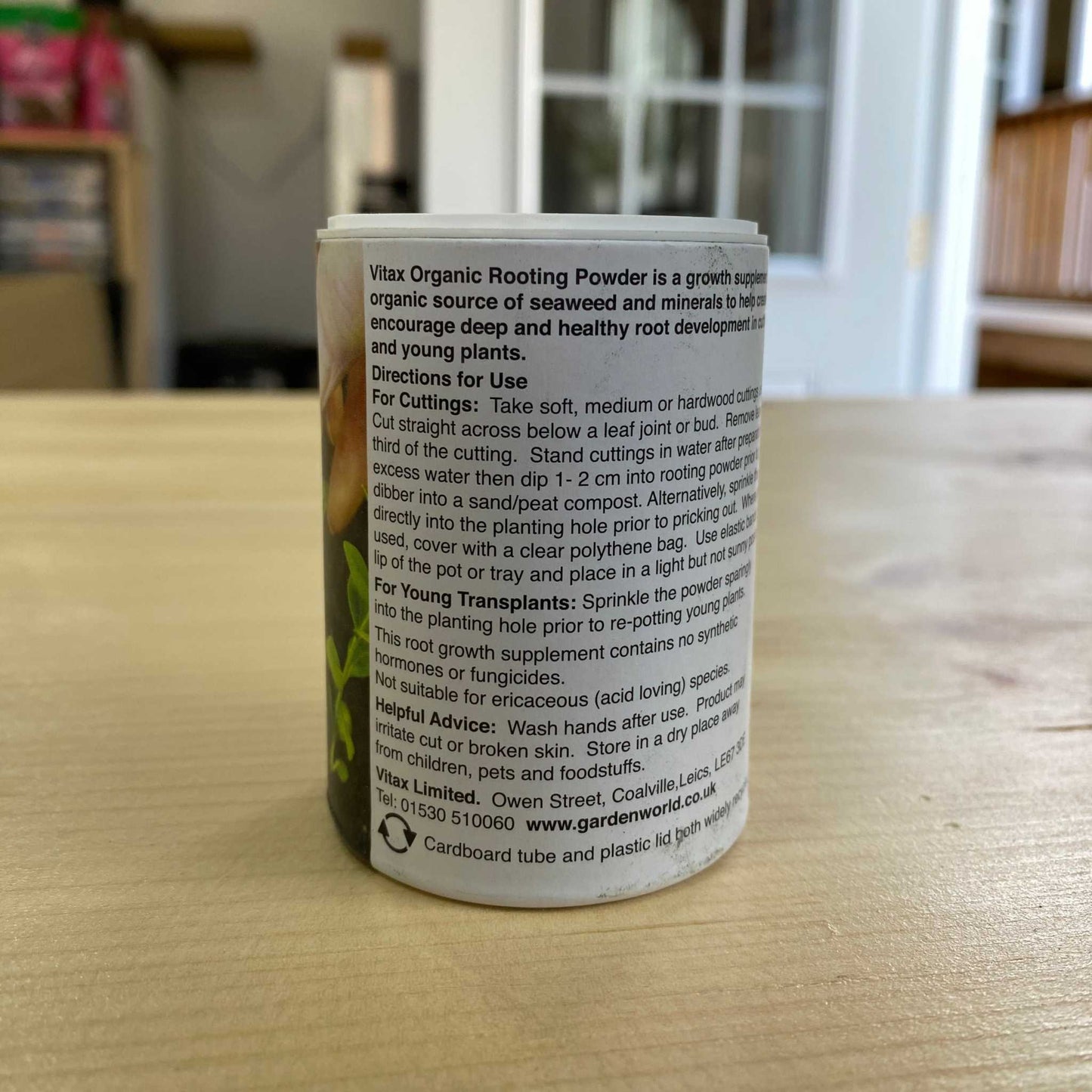 Organic Rooting Powder container on wooden surface, promotes healthy root development in plants.