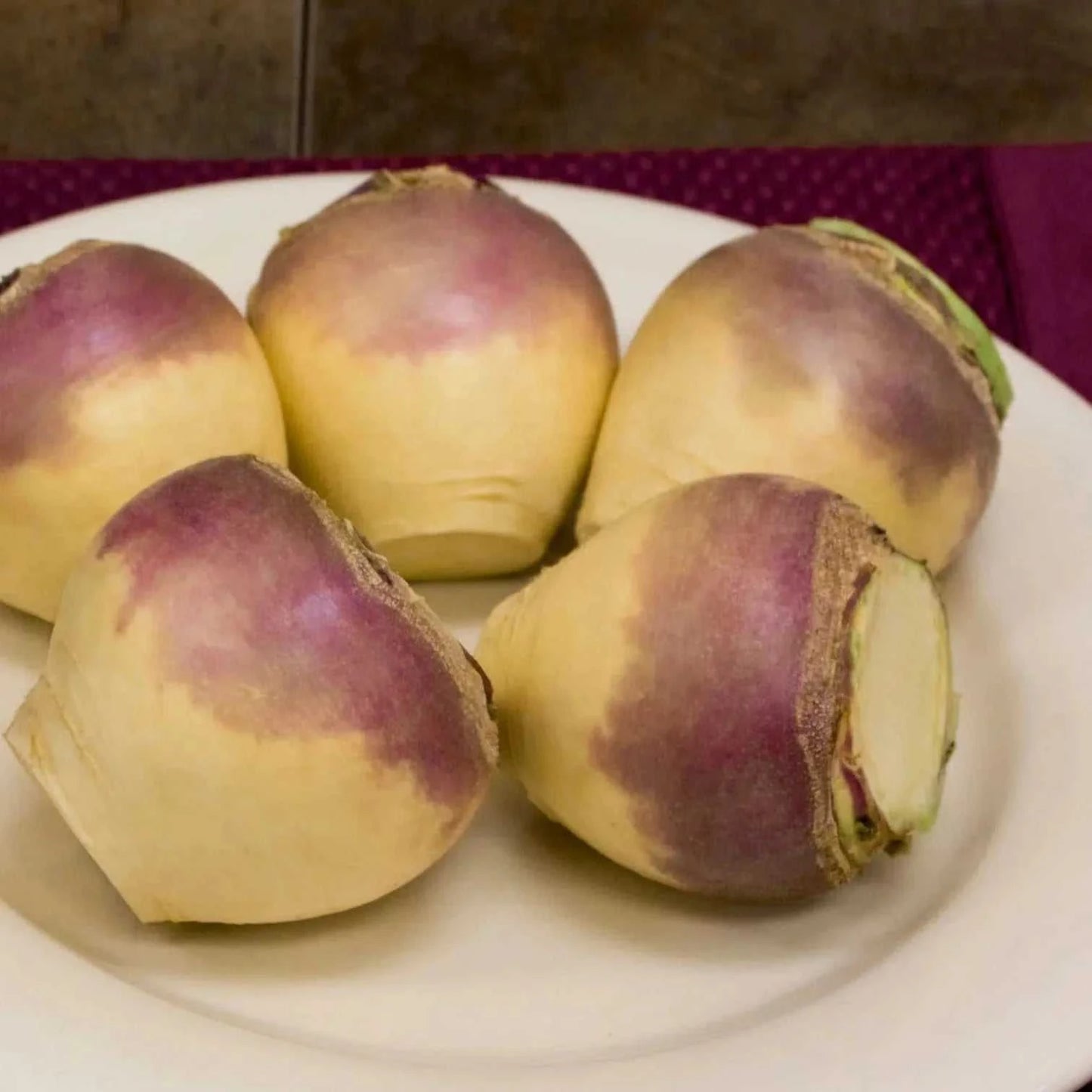Laurentian Rutabaga - Heirloom seeds with smooth, round shape and vibrant purple tops on a white plate.