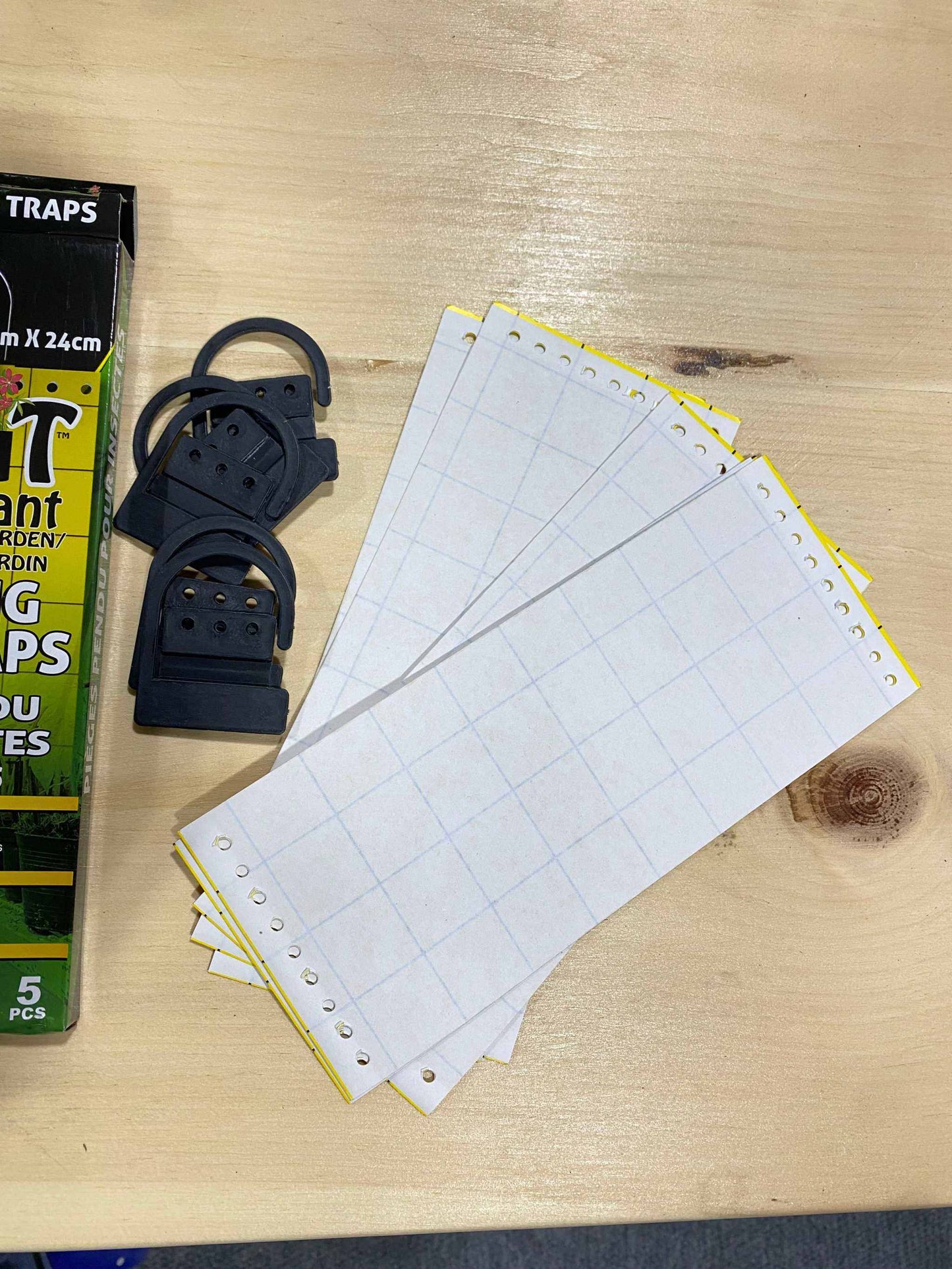 Yellow insect strip traps with grid lines for natural pest control displayed on a wooden surface.