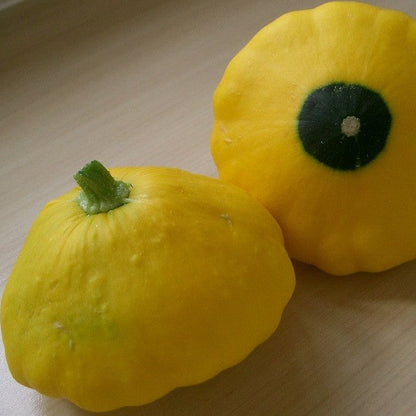 Vibrant golden-yellow scallop squash with unique shape on wooden surface.