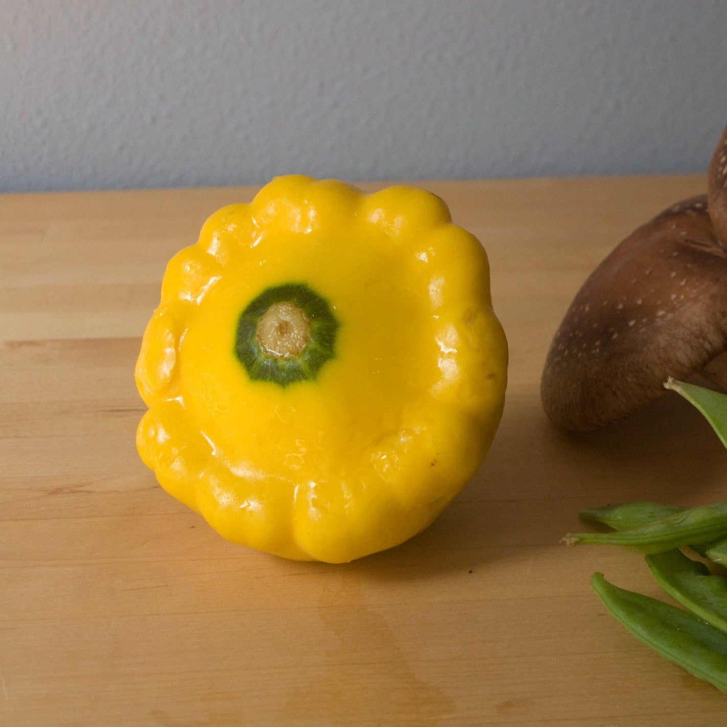 Yellow scallop squash on a wooden surface.