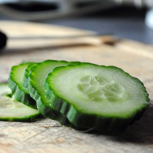 Sliced Cucumber Sweeter Yet Hybrid on a wooden cutting board.