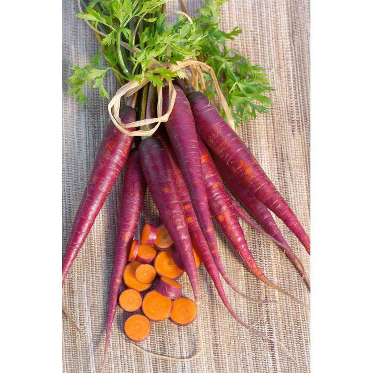 Cosmic Purple Carrot – Heirloom Seeds NT with vibrant purple skin and bright orange centers displayed on a woven surface.