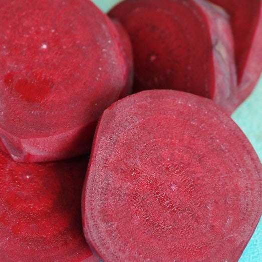 Close-up of sliced Cylindra Beets Matches Seeds, showcasing vibrant red color and smooth texture.